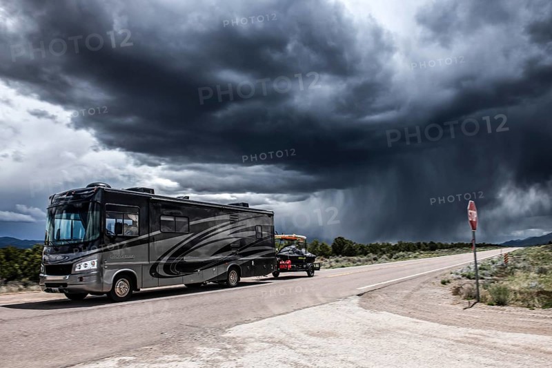 Motorhome with boat trailer driving through wild thunderstorm and rain clouds over Highway 50, Loneliest Road in America, Ely, Nevada, USA, North America