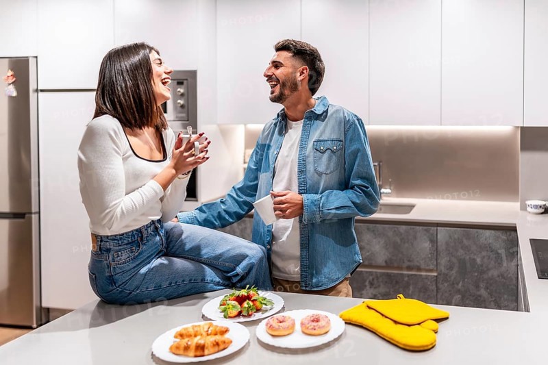 Young couple laughing and having breakfast in a modern kitchen, enjoying a moment of happiness together
