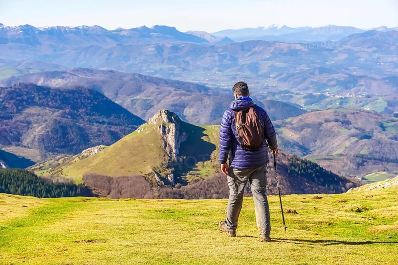 Male hiker enjoying the view of the mountains and valleys of the basque country while trekking through mount txindoki in gipuzkoa