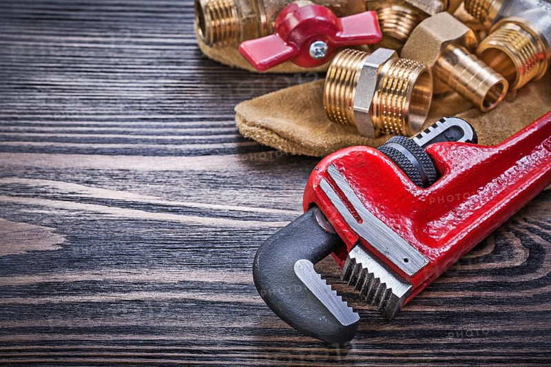 Composition of protective gloves brass plumbing equipment on wooden board