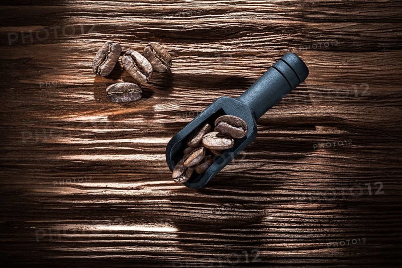 Black coffee seeds in scoop on vintage wooden board