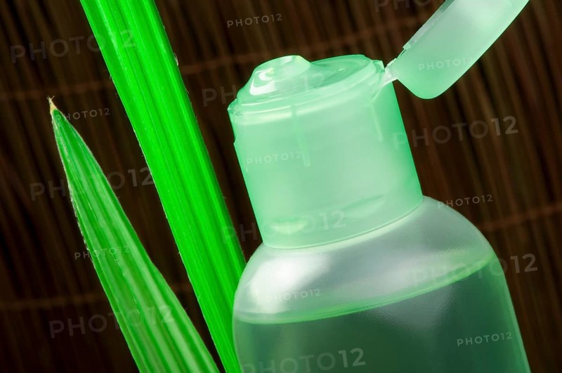 Green cosmetic bottle and green leaf. Studio shot