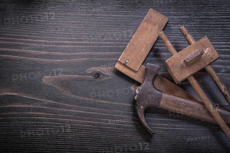 Age-old claw hammer square ruler carpenter gauge on wood board