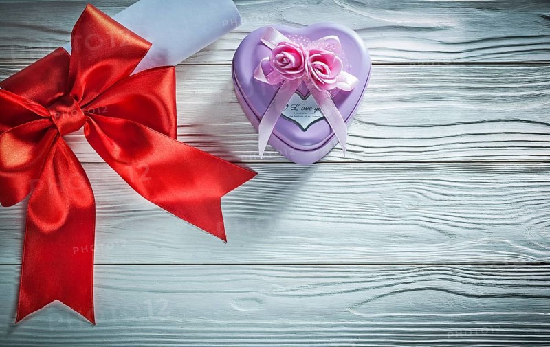 Paper roll with red bow metal gift box on wooden board holidays concept