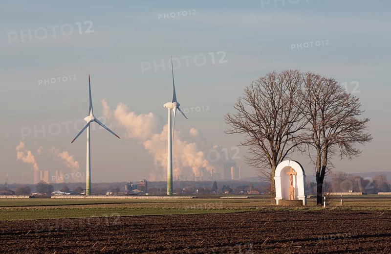 18th century wayside shrine flanked by two lime trees, behind it two wind turbines and coal-fired power stations (Rhenish lignite mining area)