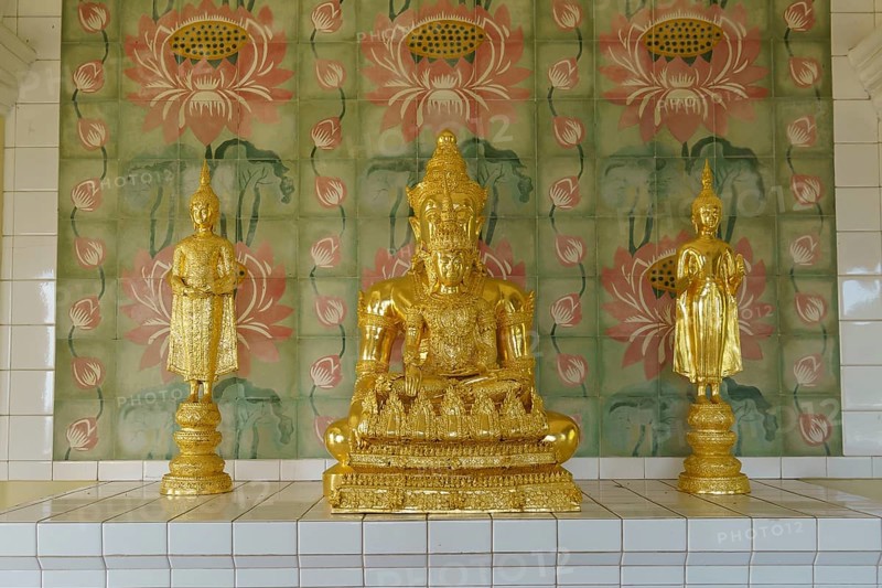 Three golden statues on a pedestal in front of ornately decorated walls inside the temple, penang, malaysia