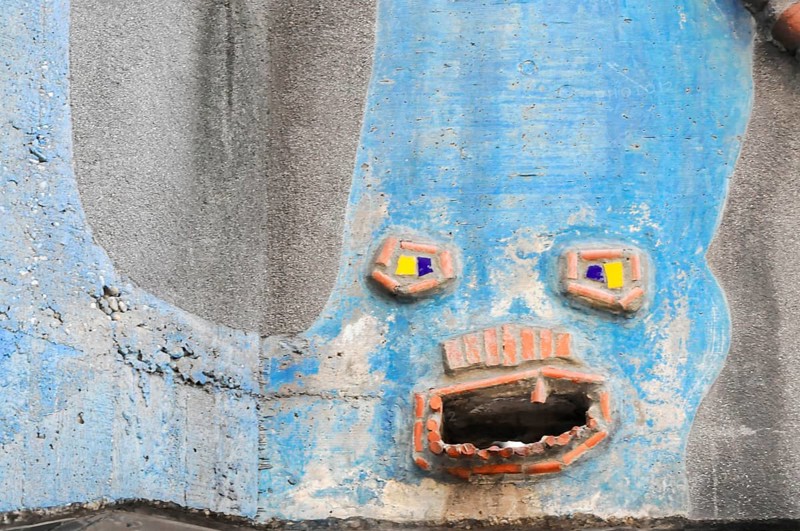 Detail of the coloured façade of the Hundertwasser House, Hundertwasser House, residential building, Vienna, Blue wall detail in the shape of a face showing creative and organic design, Vienna, Austria, Europe