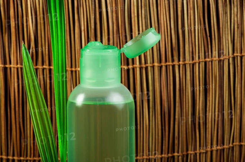 Green cosmetic bottle and green leaf. Copy space