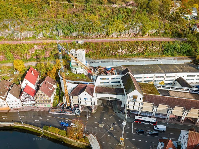 Urban area with construction site next to a river, red roofs and autumnal trees, extension of the ZOB Calw tower on the new track of the Hermann Hesse railway, Calw, Black Forest, Germany, Europe