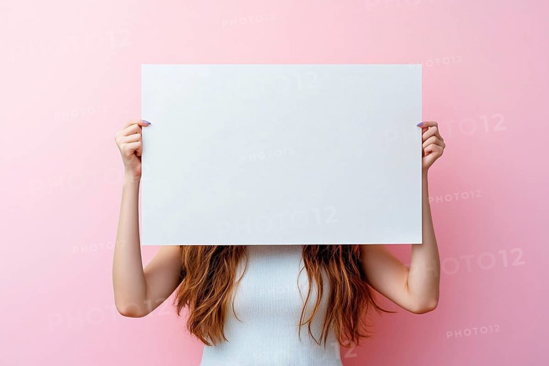 White empty sign being held by woman in front of pastel pink studio background. Generative AI, AI generated