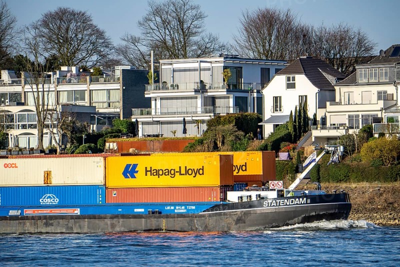Container cargo ship on the Rhine near Düsseldorf-Bockum, villas on the banks of the Rhine, the neighbourhood in district 5 is one of the most expensive residential areas in Düsseldorf, North Rhine-Westphalia, Germany, Europe