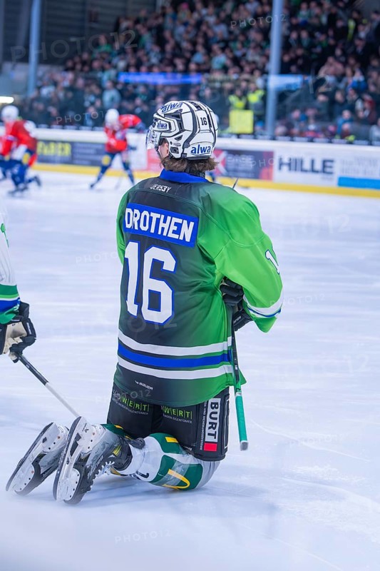 An ice hockey player kneels on the ice in a green jersey during a game, Heilbronner Falken Vs Bietigheimer Steelers, Heilbronn, Germany, Europe