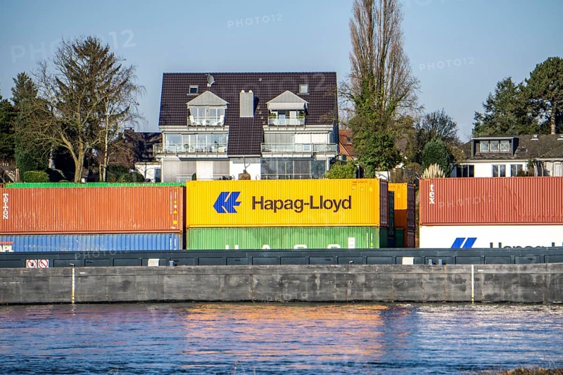 Container cargo ship on the Rhine near Düsseldorf-Bockum, villas on the banks of the Rhine, the neighbourhood in district 5 is one of the most expensive residential areas in Düsseldorf, North Rhine-Westphalia, Germany, Europe