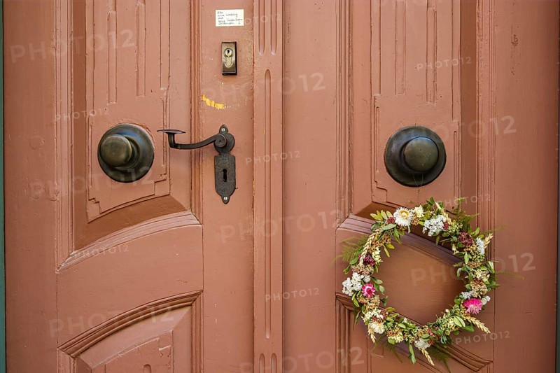 Detail of an antiquated front door with floral wreath and no advertising sign in a building on the Krämerbrücke in the historic city centre of Erfurt, Thuringia, Germany, Europe