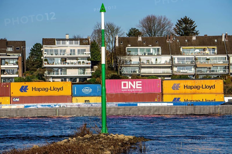 Container cargo ship on the Rhine near Düsseldorf-Bockum, villas on the banks of the Rhine, the neighbourhood in district 5 is one of the most expensive residential areas in Düsseldorf, North Rhine-Westphalia, Germany, Europe