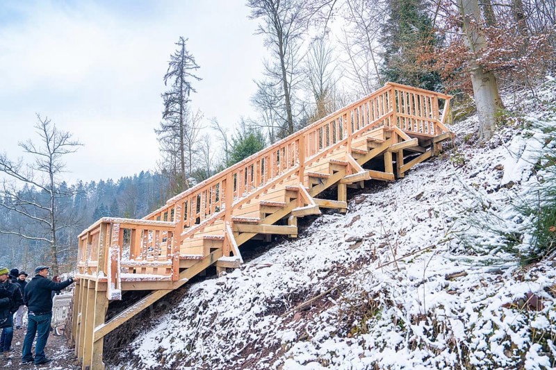 Snow-covered wooden stairs in the winter forest, with people nearby, New wooden footbridge in Calw city garden, Calw, Black Forest, Germany, Europe