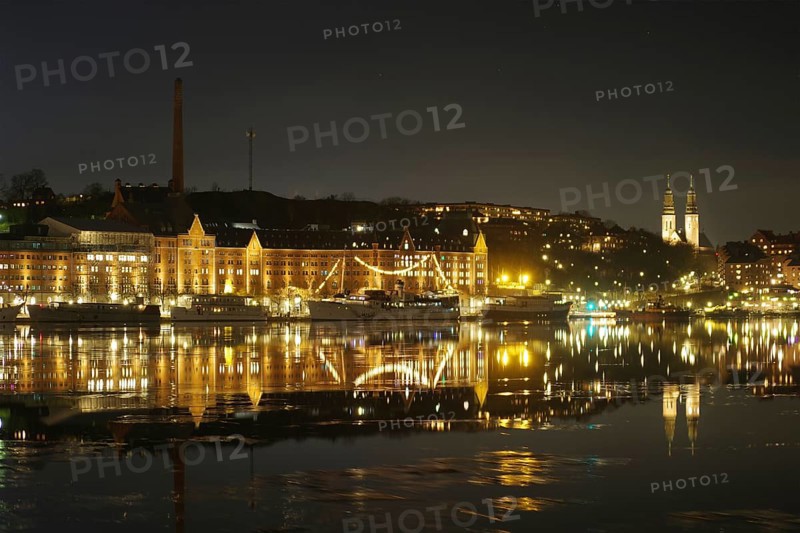 Shore view at night with illuminated buildings, ships and church towers, winter, ice, capital, Södermalm, Stockholm, Sweden, Europe