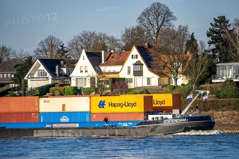 Container cargo ship on the Rhine near Düsseldorf-Bockum, villas on the banks of the Rhine, the neighbourhood in district 5 is one of the most expensive residential areas in Düsseldorf, North Rhine-Westphalia, Germany, Europe