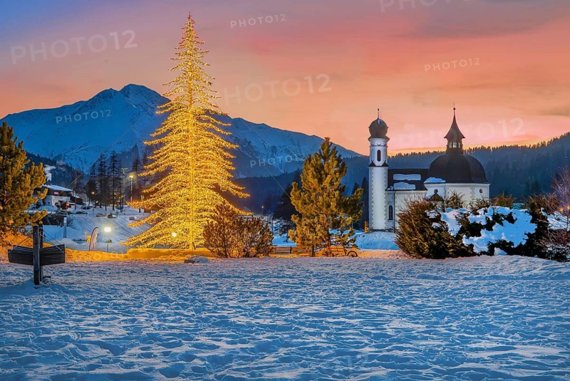 Seekirchl with artificially illuminated winter fir tree and Hocheder 2797m at dusk in winter, Seefeld, Seefeld Plateau, Tyrol, Austria, Europe