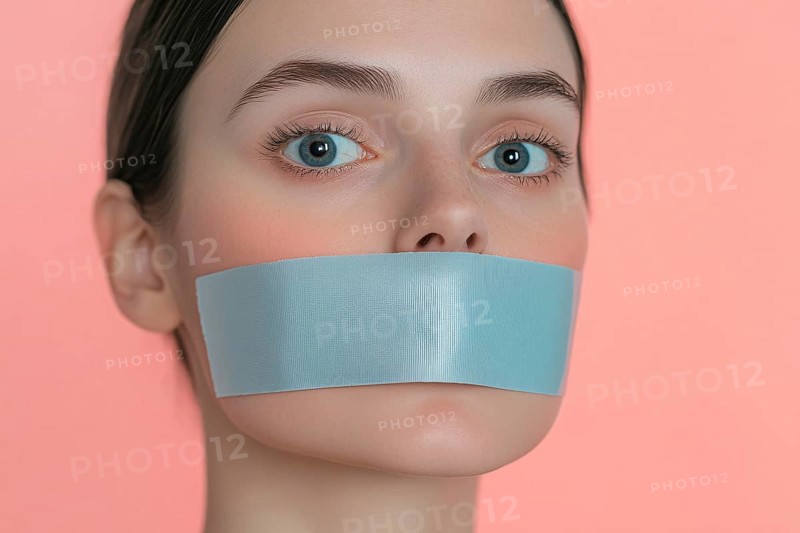 Young woman silenced with gray tape over her mouth in front of pink studio background. Generative AI, AI generated