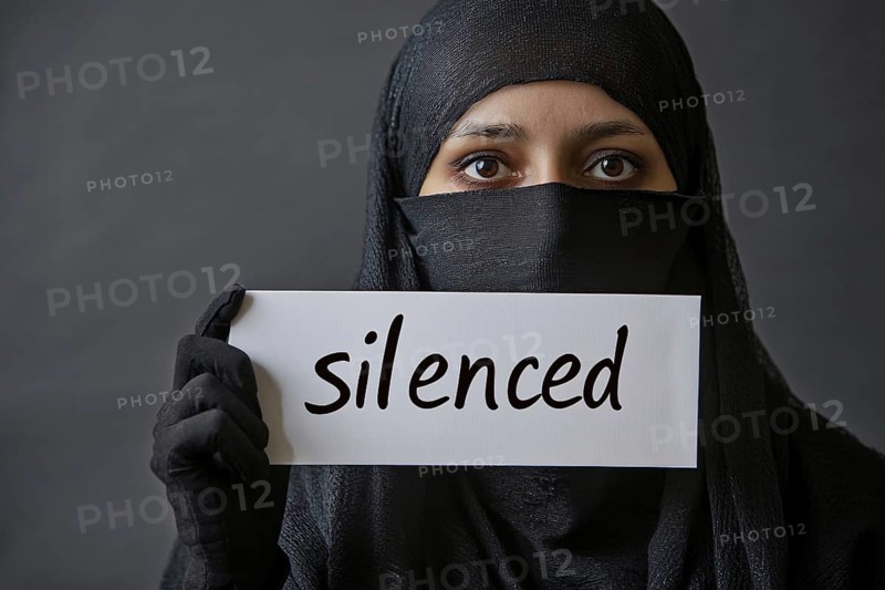 Young muslim woman with black niqab holding up sign with text 'silenced'. Generative AI, AI generated