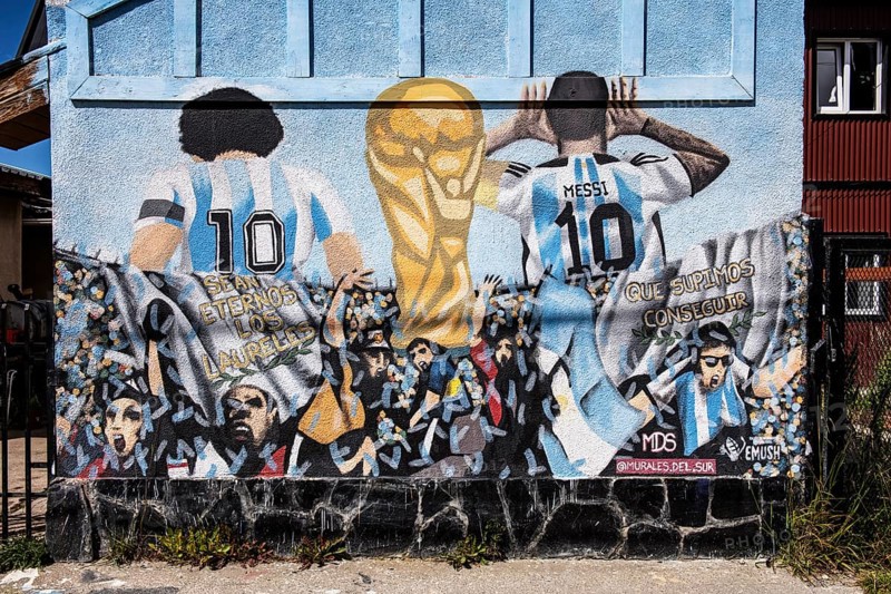 Diego Maradonna and Lionel Messi with the World Cup trophy on a house wall in Ushuaia, Argentina, South America