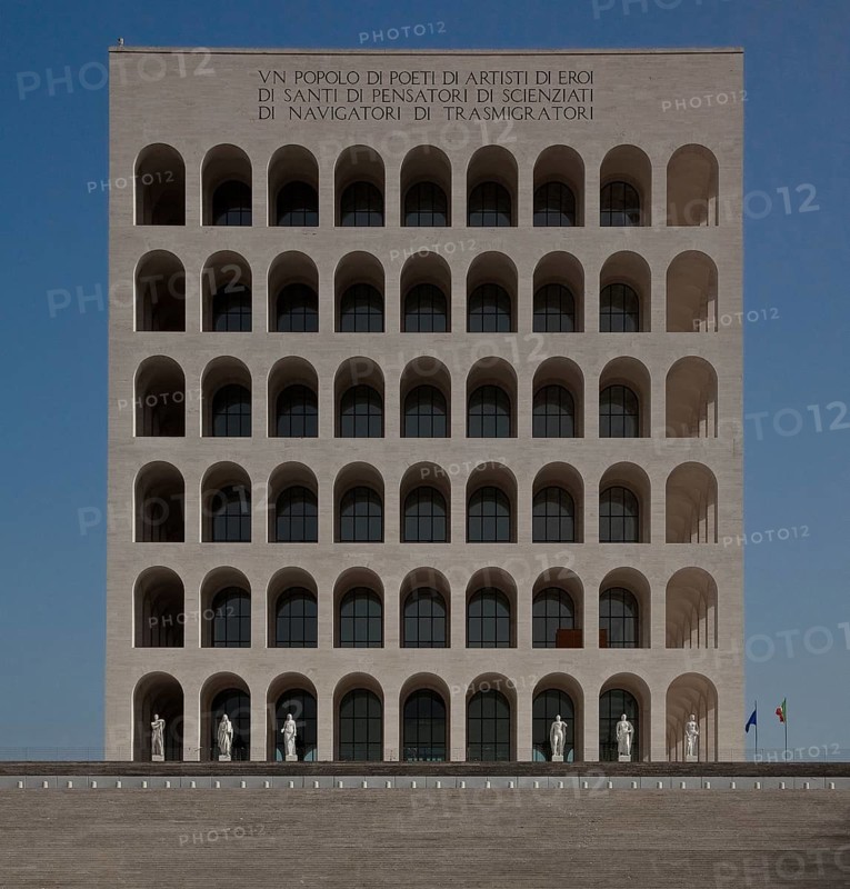 Begun in 1937, so-called rectangular Colosseum, Colosseo quadrato, height 68m, from north-west, On each of the four sides of the ashlar building, above the arcades, the following motto can be read in Roman majuscules: UN POPOLO DI POETI DI ARTISTI DI EROI DI SANTI DI PENSATORI DI SCIENZIATI DI NAVIGATORI DI TRASMIGRATORI. Translated, this means: A people of poets, of artists, of heroes, of saints, of thinkers, of scientists, of sailors, of travellers