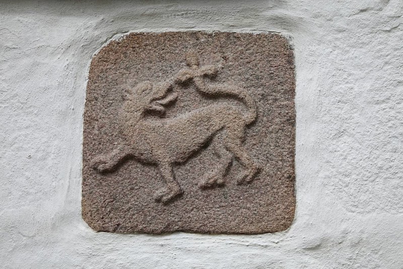 DNK, Langeland, Skroebelev, village church, ca. 12th century, Exteriör, granite sculpture, south wall, lion bites its tail, St., Sankt, Saint