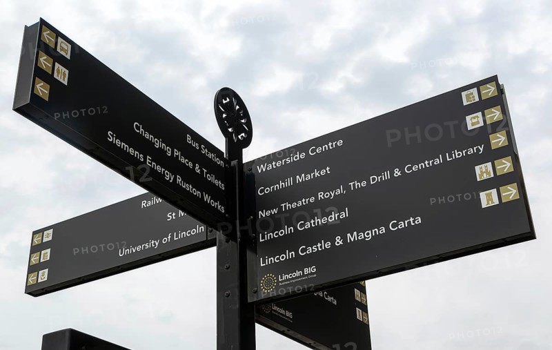 Looking up at signpost pointing to places of interest, city of Lincoln, Lincolnshire, England, UK