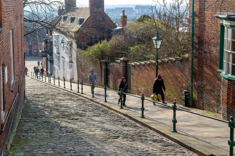 People walking up Steep Hill cobbled street, Lincoln, Lincolnshire, England, UK