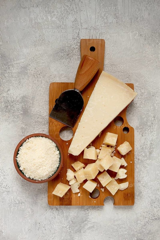 Freshly sliced and grated cheese, parmesan cheese, Gran gusto. Grana padano. on a wooden chopping board, rustic style, no people