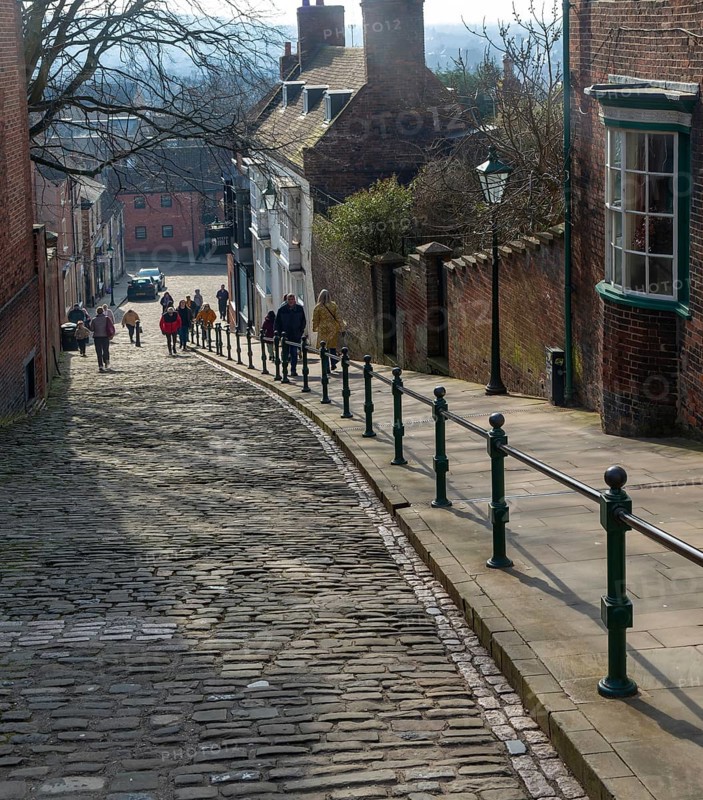 People walking up Steep Hill cobbled street, Lincoln, Lincolnshire, England, UK