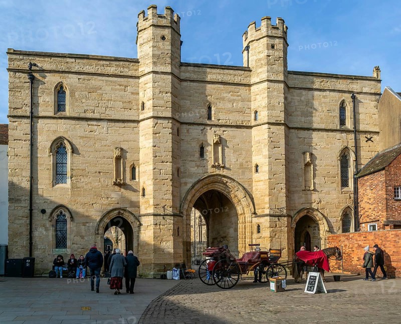 Sun shining on Exchequer Gate with horse carriage rides, Minster Yard, city of Lincoln, Lincolnshire, England, UK