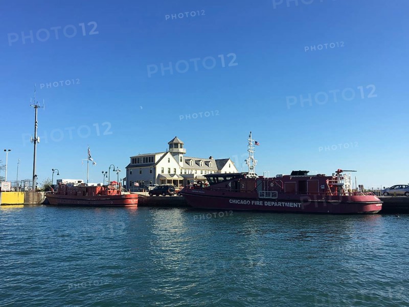 Fireboats on the banks of a river next to a historic building under a blue sky, chicago, usa