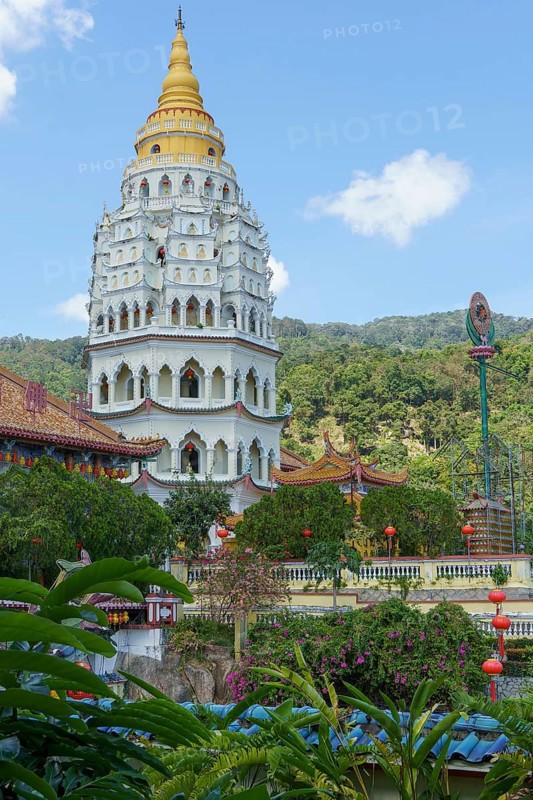 Imposing pagoda with golden spire, surrounded by green hills and blue sky, penang, malaysia