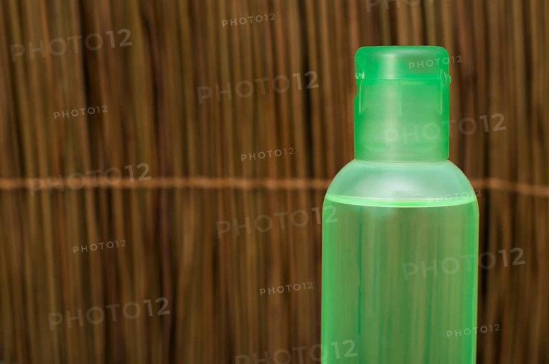 Green transparent cosmetic bottle. Wooden background