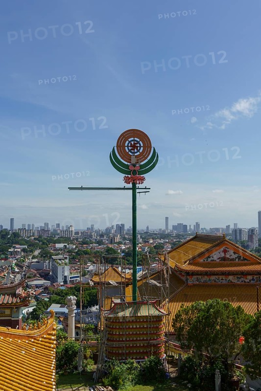 A temple with detailed roof decorations and city skyline in the background, penang, malaysia