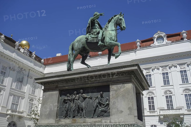 Bronze statue of a horseman on a pedestal in front of a historic building, vienna, austria