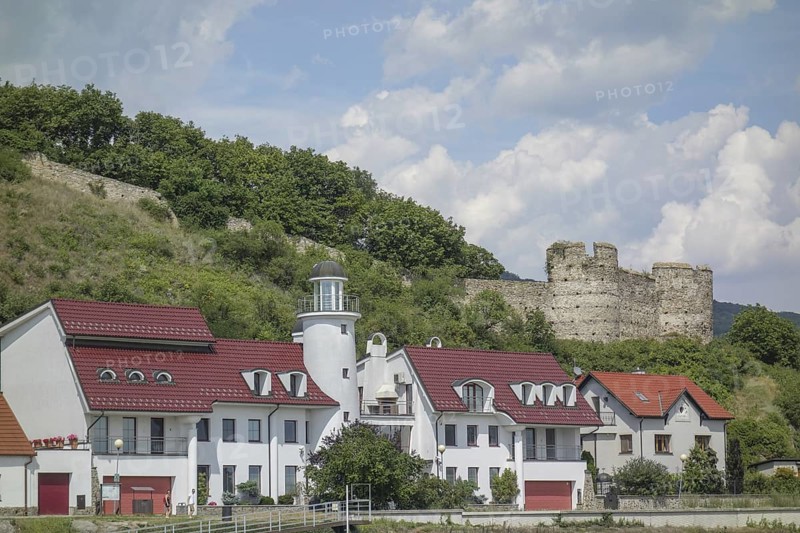 White houses with red roofs and a tower in front of an old castle on a hill, donau, austria