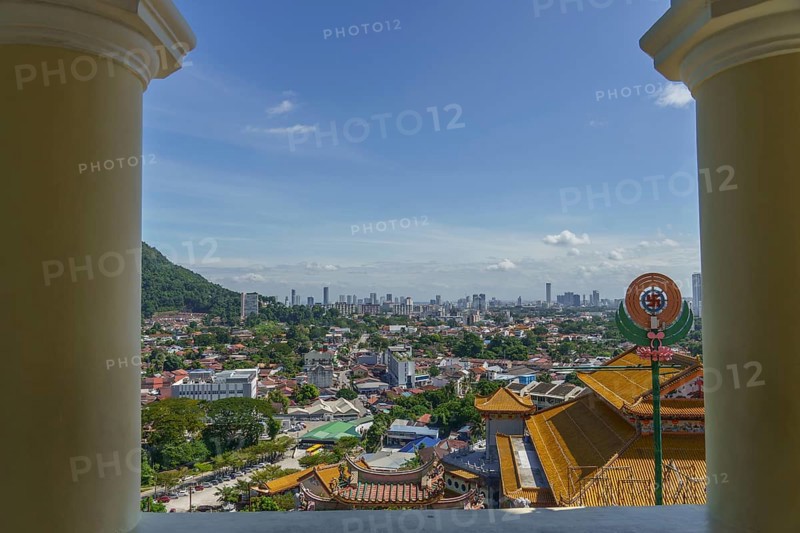 View of a city with temple buildings and modern structures under a clear sky, penang, malaysia