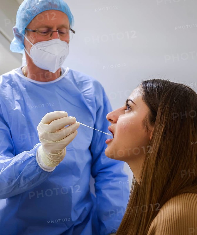 Essen, North Rhine-Westphalia, Germany - Corona test centre Grugahalle open for free citizen test, Covid rapid test, a doctor tests a young woman for the coronavirus using a throat swab, from 8 March, German citizens can be tested for corona once a week free of charge at the rapid test centre