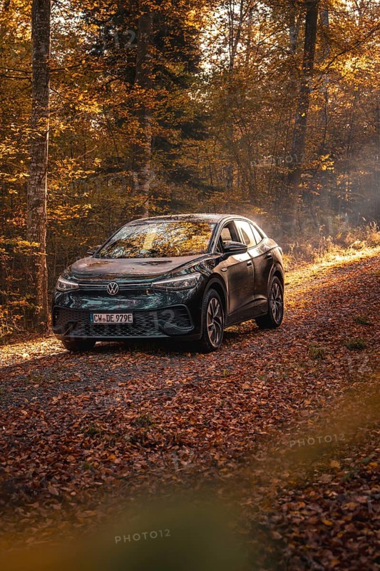 Car in an autumnal forest illuminated by sunbeams, calm atmosphere, electric car VW ID5, Gechingen, Black Forest, Germany, Europe