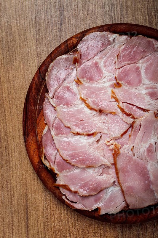 Sliced pork neck, boiled and smoked, smoked pork neck, sliced, on a wooden chopping board, close-up