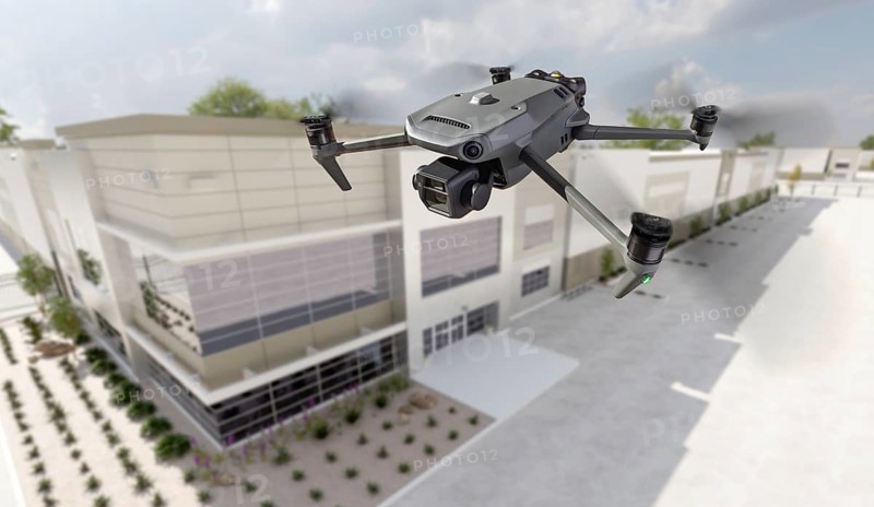 Unmanned aircraft system quadcopter drone UAV in the air near corporate industrial building
