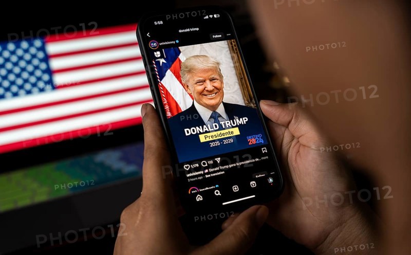 In this photo illustration, a person looks Donald Trump image on a smartphone after results of U.S. elections on a television in Guwahati, India on 6 November 2024. Donald Trump has won the 2024 US presidential election and a second term in the White House, four years after losing the 2020