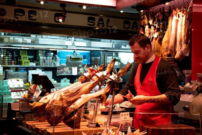 Barcelona, Spain, January 26 2019: Bucher at a meat farmer market counter. Various meat slices at a grocery store. La Boqueria, Barcelona Spain, Europe