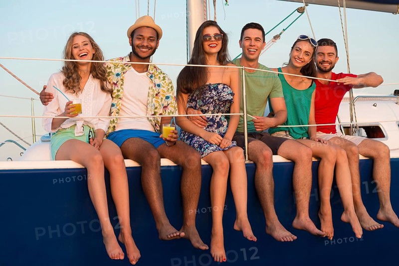 Loving couples relaxing on a yacht. Happy young people sailing on the yacht. Beautiful guys and girls spend the weekend on a yacht. Cruise on a yacht at sea. Party on a yacht