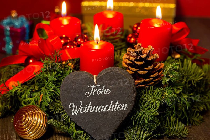 Heart with the inscription FROHE WEIHNAHCHTEN in front of an Advent wreath and Christmas decorations