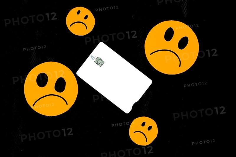 Illustration of orange paper emoticon faces cut out with sad gesture and a white bank card on black background. concept of ruin sadness sadness dissatisfied with bank credit cards