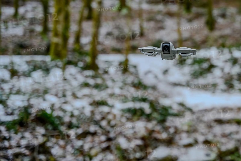A drone flies over a wintry forest with light snowfall, The icy waterfall in the Perlbachtal valley near Bogen, Lower Bavaria